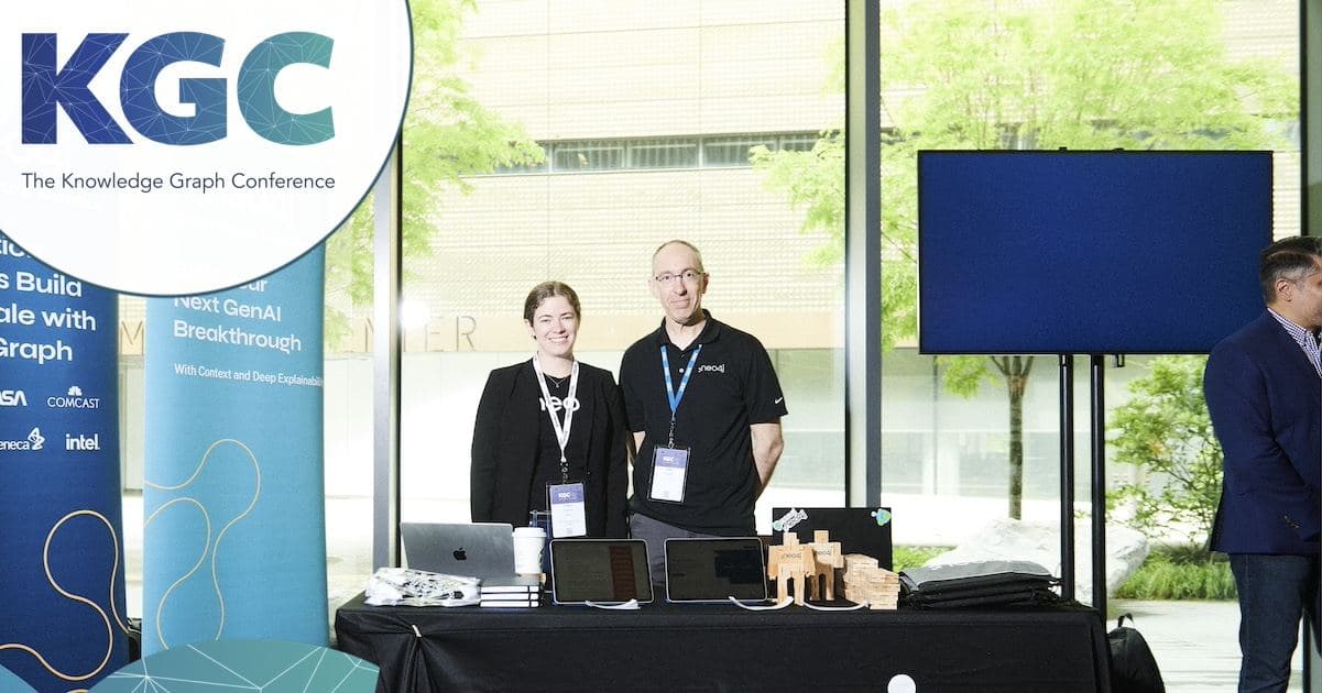 Two people at a sponsor table beside the KGC banner at KGC 2025